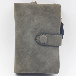 Detail view of a matte grey-green tri-fold wallet with snap closure and side zipper metal