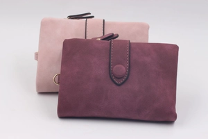 Macro detail of trifold matte PU leather wallets in dusty pink and burgundy tones