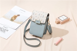 Détail du sac de téléphone en cuir bleu clair et blanc crème avec motifs botaniques
