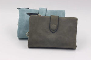Detail view of matte tri-fold wallets in green and blue with gold hardware