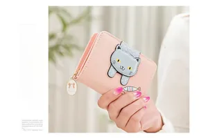 Detailed view of pink leather wallet with blue cat buckle and golden heart charm pendant