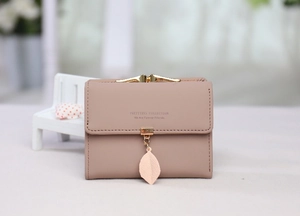 Close-up of pink tri-fold faux leather wallet with gold leaf pendant and brand lettering