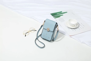 Dettaglio della mini borsa a tracolla azzurra a fiori con fibbia dorata e texture