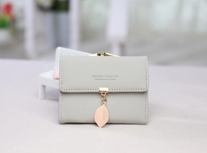 Detail of light green PU leather tri-fold wallet with golden leaf pendant and flap closure