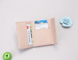 Detail view of pink trifold wallet interior with card slots and a secure snap button closure