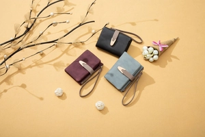 Detail of three matte leather women wallets in black, burgundy and blue with gold buckles