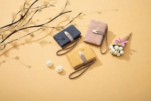 Detailed view of matte textured handbags in navy, dusty rose, and mustard with wrist straps