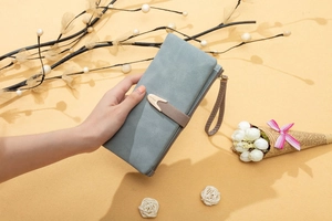 Detail of grey-blue matte PU leather long wallet with wrist strap and gold buckle