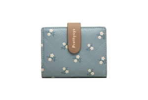 Close-up of blue floral quilted wallet featuring a brown leather buckle and secure stitching