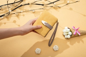 Detail of yellow matte leather wallet showing gray wrist strap and metallic buckle