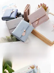 Detail of elegant pastel leather wallets featuring gold leaf pendants and logo stamp