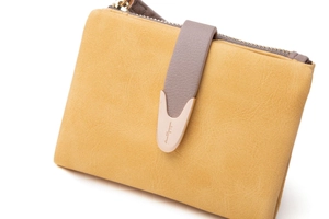 Detail of yellow matte leather wallet showing top zipper and metal teardrop buckle