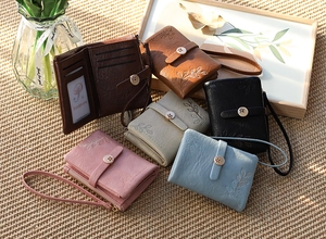 Close-up of elegant leaf embossing and metallic floral clasp on leather wallets