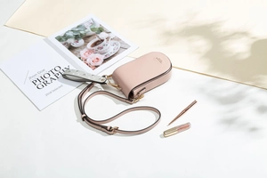 Dettaglio della mini borsa a tracolla rosa pallido in PU con logo dorato e cinturino