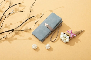 Detail of blue-grey matte PU leather long wallet featuring metal buckle and wrist strap