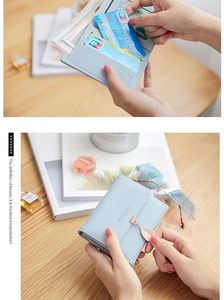 Detail view of a light blue tri-fold wallet with card slots and a leaf pendant
