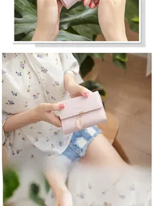 Close-up of pink PU leather wallet with delicate metal leaf pendant and branded logo