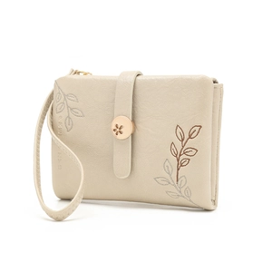 Detail of beige faux leather wallet with floral embroidery and metal flower charm