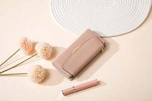 Detail of long pale pink wallet showing golden wheat clasp and smooth faux leather texture