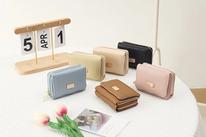 Flat lay of colorful PU leather short wallets with gold logo plates on a white desk
