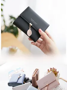 Detail of multi-color tri-fold wallets featuring metal leaf pendants and matte leather finish