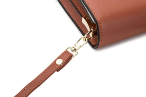 Detail of gold metal hardware and stitching on brown leather crossbody phone bag strap
