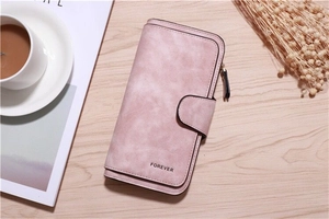 Close-up of pink faux suede long wallet with snap buckle on a wooden desk setup