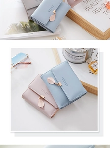 Close-up of three-fold women's wallets with gold leaf charms and brand logo