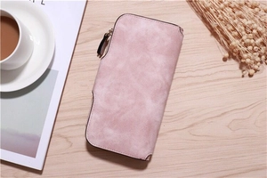 Pink long wallet with matte finish and zipper detail on light wood background