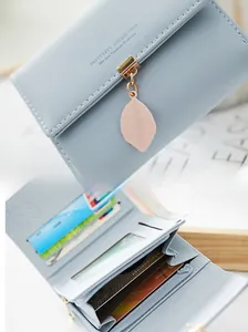 Macro shot of light blue trifold wallet showing the metal clasp and internal card slots