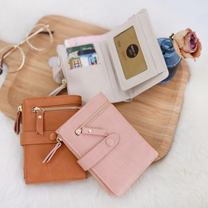 Women compact tri-fold PU leather wallets in beige, orange and pink on a tray