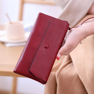 Close-up of wine red matte leather wallet with hand strap and embossed brand detail