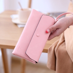 Detail of pink PU leather long clutch wallet with wristlet held by a model on a desk