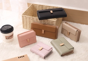 Detailed view of women's long wallets featuring gold shield buckles and multi-card slots