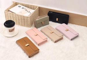 Flat lay of multiple long PU leather wallets in diverse pastel colors on white faux fur
