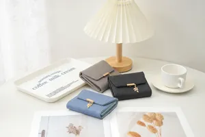 Vue détaillée de portefeuilles matelassés avec pendentifs feuilles en gris, noir et bleu