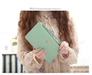 Detail of fruit green PU leather wallet with crown embossing held by a female model