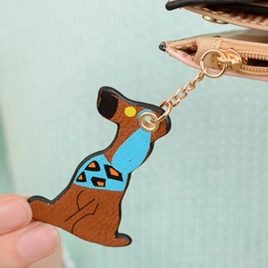 Close-up of a brown cartoon dog charm with geometric patterns on a beige wallet zipper