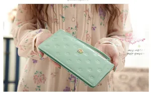 Close-up of mint green PU leather long wallet with embossed crowns and enamel metal charm