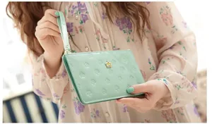 Close-up of mint green patent leather purse with embossed crown pattern and metal clasp