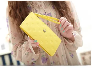 Detail of yellow PU leather wallet with embossed crown pattern and matching wristlet strap