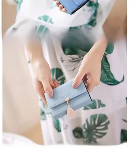 Close-up of light blue PU leather wallet with golden buckle and pink leaf pendant