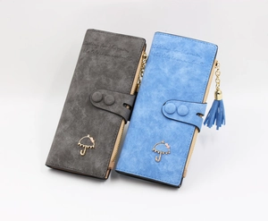 Detail of long matte wallets in grey and blue with metal charms and decorative tassels