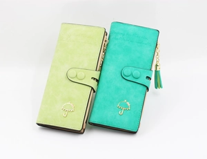 Detail of long wallets in mint and green faux suede with tassels and umbrella charms