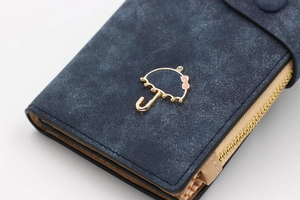 Close-up of matte dark blue long wallet featuring a gold umbrella icon and bow detail