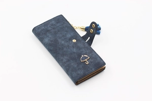 Detail of navy blue matte leather wallet with golden umbrella accent and tassel