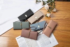 Flat lay of multiple colorful PU leather wallets on a wooden desk with floral decor
