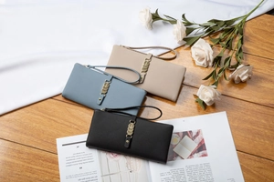 Detailed view of long wallets in black, blue, and apricot with litchi grain texture