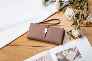 Close-up of a long leather wallet in dark brown with a metal buckle and wristlet strap