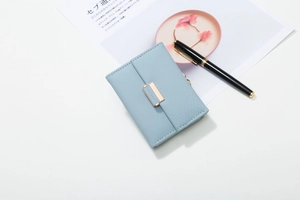 Detail of light blue quilted PU leather tri-fold wallet with elegant gold metal buckle closure